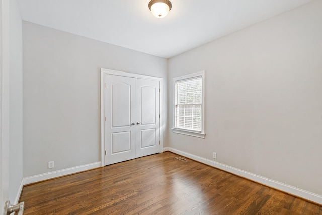 unfurnished bedroom with dark wood-type flooring and a closet