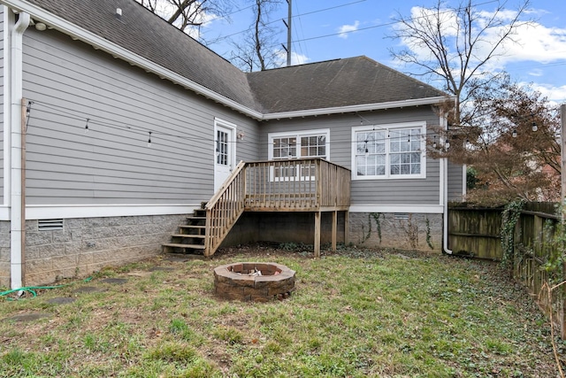 rear view of house featuring a yard, a fire pit, and a deck