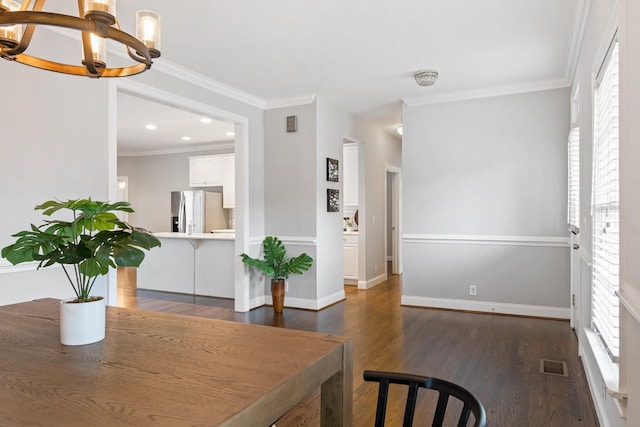 dining room with a chandelier, plenty of natural light, dark wood-type flooring, and ornamental molding