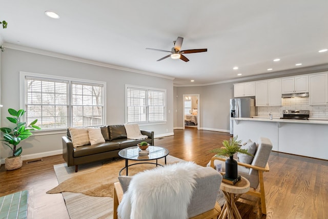 living room featuring ceiling fan, a healthy amount of sunlight, dark hardwood / wood-style floors, and ornamental molding