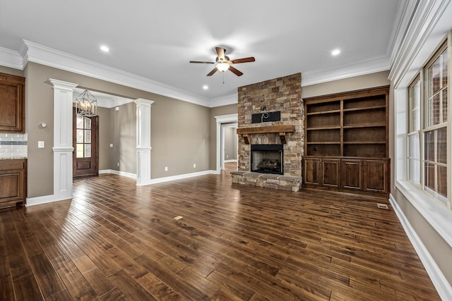 unfurnished living room with decorative columns, a stone fireplace, dark hardwood / wood-style flooring, and ornamental molding