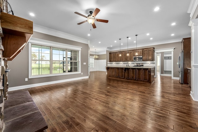 unfurnished living room featuring crown molding, sink, dark wood-type flooring, and ceiling fan with notable chandelier