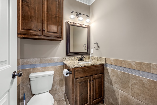 bathroom featuring vanity, toilet, ornamental molding, and tile walls