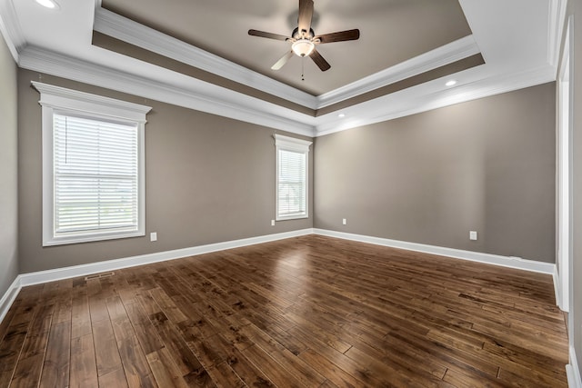 empty room with ornamental molding, a raised ceiling, ceiling fan, and dark wood-type flooring