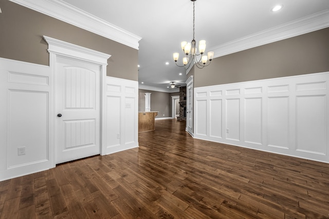 unfurnished dining area featuring ceiling fan with notable chandelier, dark hardwood / wood-style floors, and ornamental molding