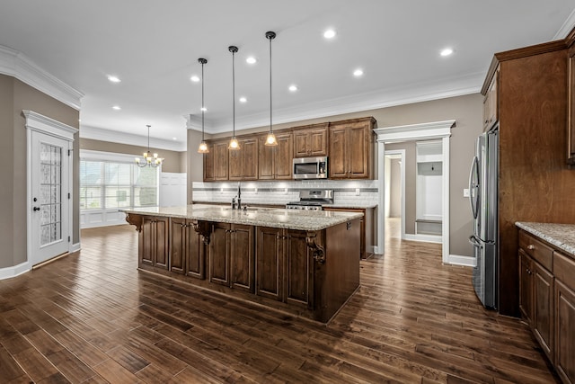 kitchen featuring a kitchen island with sink, dark wood-type flooring, pendant lighting, and appliances with stainless steel finishes