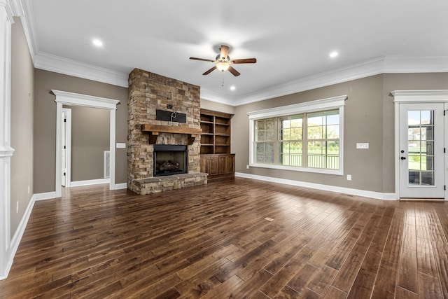 unfurnished living room with a stone fireplace, ceiling fan, crown molding, and dark wood-type flooring