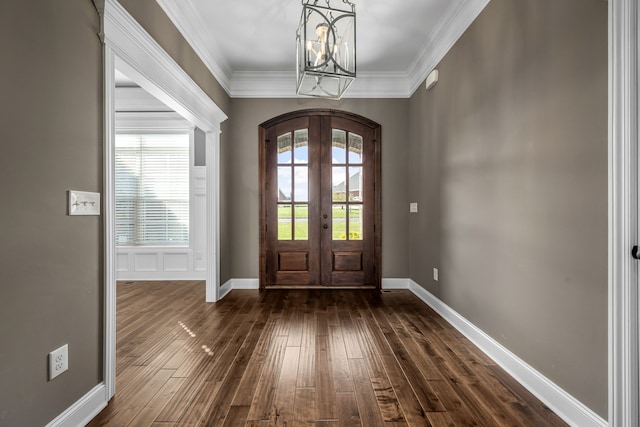 entrance foyer featuring french doors, dark wood-type flooring, ornamental molding, and a notable chandelier