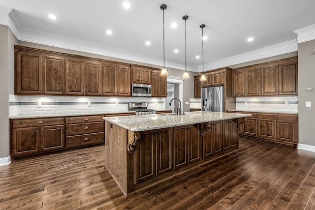 kitchen featuring a kitchen island with sink, dark wood-type flooring, hanging light fixtures, and appliances with stainless steel finishes