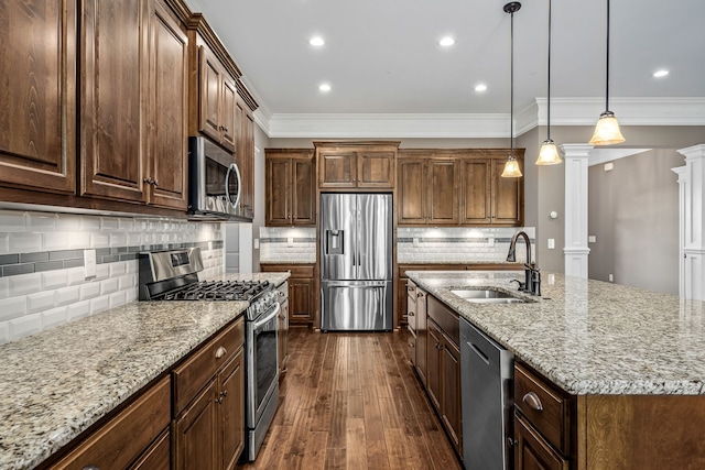 kitchen with a center island with sink, sink, decorative light fixtures, stainless steel appliances, and decorative columns