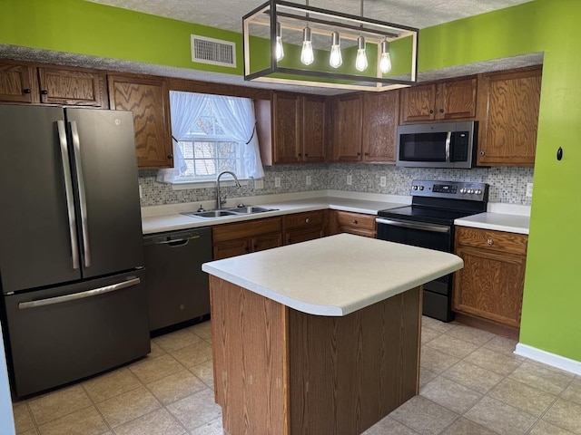 kitchen featuring a center island, hanging light fixtures, sink, a textured ceiling, and appliances with stainless steel finishes