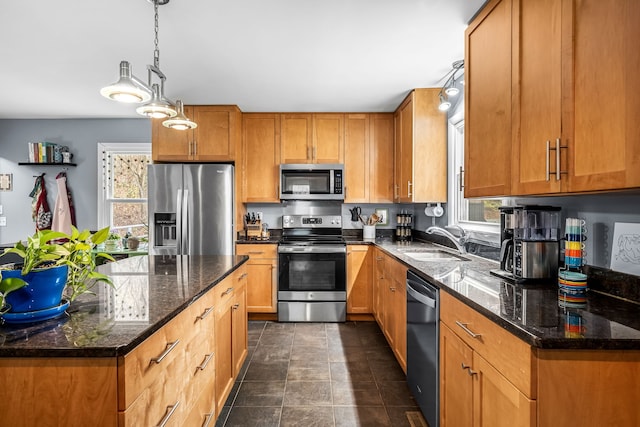 kitchen with pendant lighting, dark stone countertops, sink, and appliances with stainless steel finishes