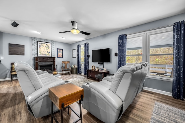 living room featuring hardwood / wood-style flooring, ceiling fan, and a large fireplace