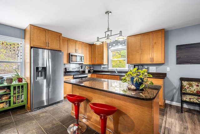 kitchen with a kitchen breakfast bar, stainless steel appliances, sink, a center island, and hanging light fixtures