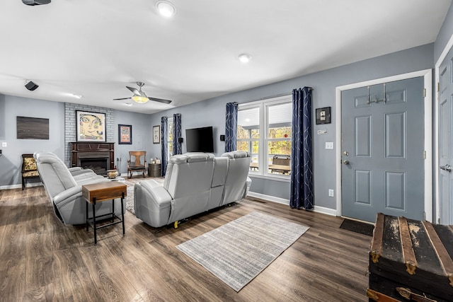 living room featuring ceiling fan, dark hardwood / wood-style flooring, and a fireplace