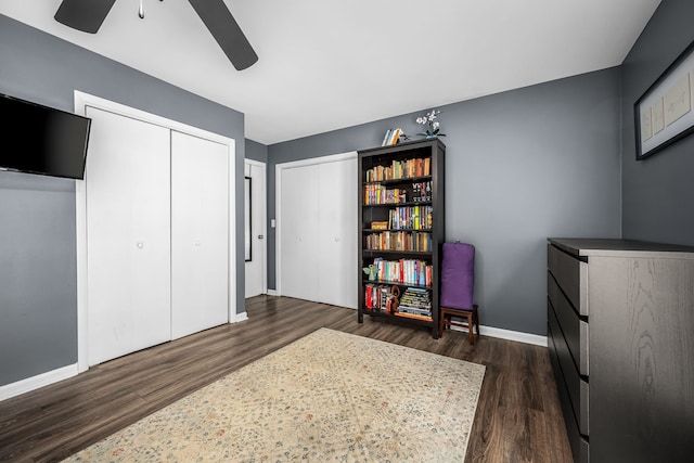 bedroom with two closets, ceiling fan, and dark hardwood / wood-style floors