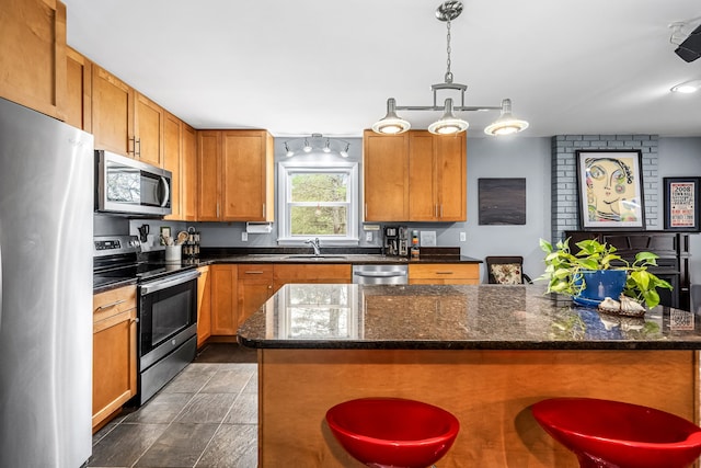 kitchen featuring a kitchen breakfast bar, a kitchen island, pendant lighting, and appliances with stainless steel finishes