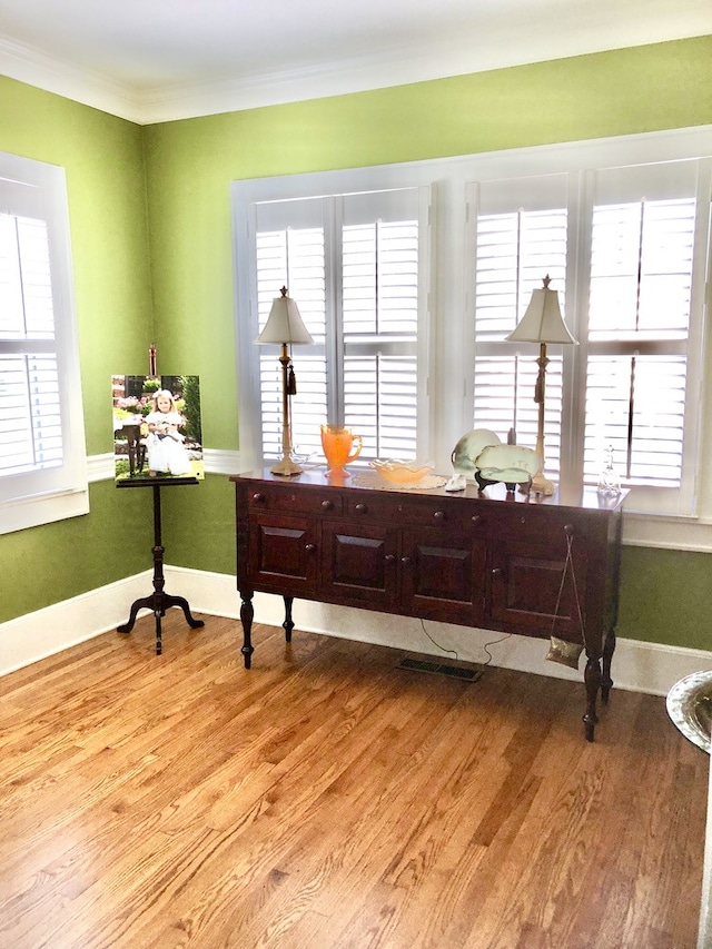 sitting room with light hardwood / wood-style floors, a wealth of natural light, and ornamental molding