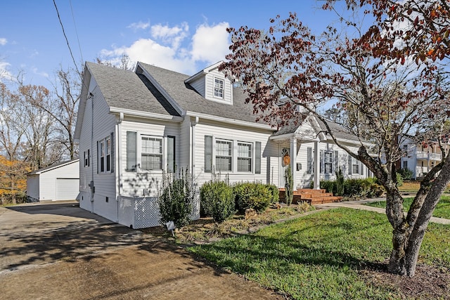 cape cod-style house featuring an outbuilding, a front yard, and a garage