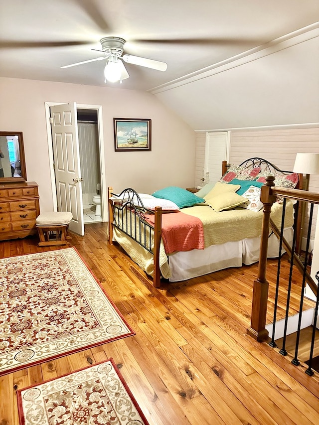 bedroom featuring hardwood / wood-style floors, ensuite bath, ceiling fan, and lofted ceiling