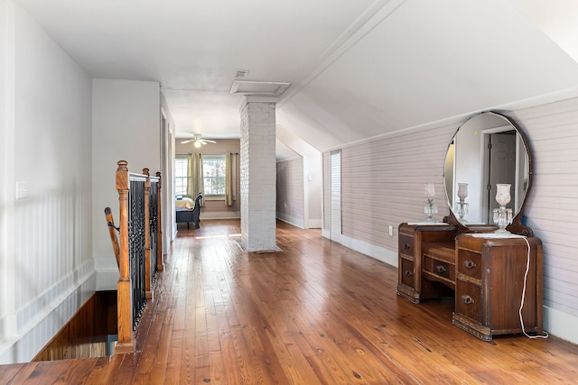 living room with decorative columns, vaulted ceiling, ceiling fan, wooden walls, and wood-type flooring