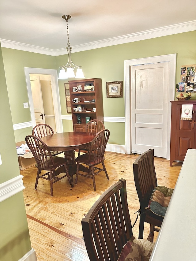 dining space featuring an inviting chandelier, light hardwood / wood-style floors, and ornamental molding