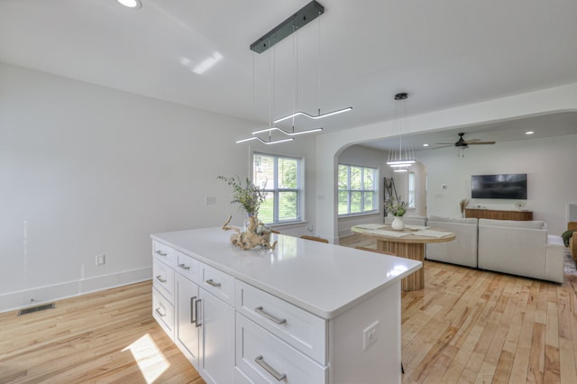 kitchen featuring pendant lighting, a center island, white cabinets, and light hardwood / wood-style floors