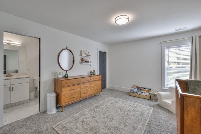 carpeted bedroom with ensuite bathroom and sink