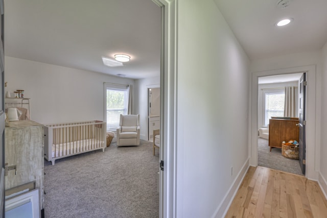 hall with light hardwood / wood-style floors and a healthy amount of sunlight