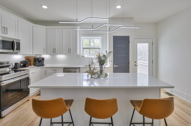 kitchen featuring a kitchen island, white cabinets, and appliances with stainless steel finishes