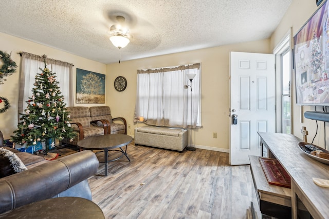 living room featuring a textured ceiling, light wood-type flooring, and ceiling fan