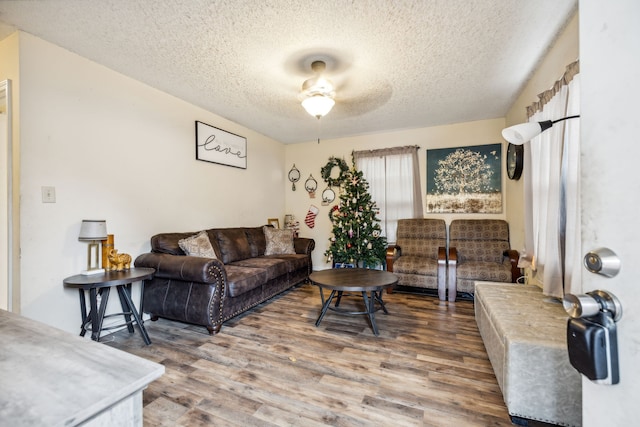 living room featuring ceiling fan, a textured ceiling, and hardwood / wood-style flooring