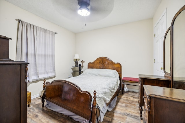 bedroom featuring ceiling fan, light hardwood / wood-style floors, and a textured ceiling