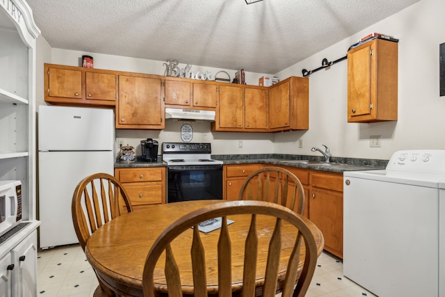 kitchen with white appliances, sink, a barn door, a textured ceiling, and washer / clothes dryer