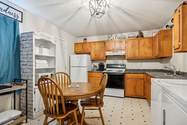 kitchen featuring a textured ceiling, sink, white appliances, and independent washer and dryer