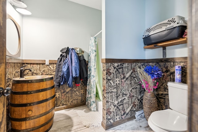 bathroom featuring wood-type flooring, toilet, and shower / bath combo with shower curtain