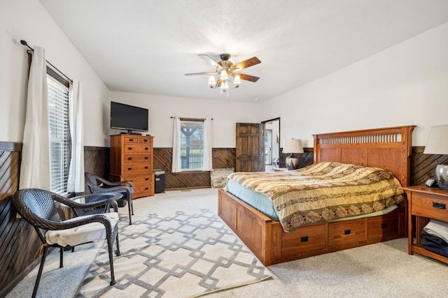 carpeted bedroom featuring ceiling fan and wooden walls