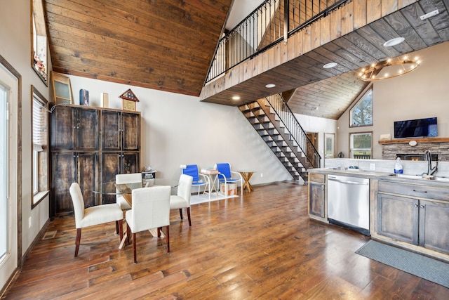 dining space featuring wood ceiling, dark wood-type flooring, sink, high vaulted ceiling, and a fireplace