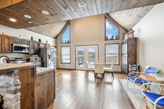 kitchen with french doors, high vaulted ceiling, appliances with stainless steel finishes, wood ceiling, and hardwood / wood-style flooring