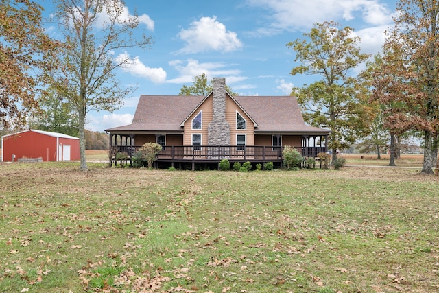 back of property featuring a lawn, a wooden deck, and an outbuilding