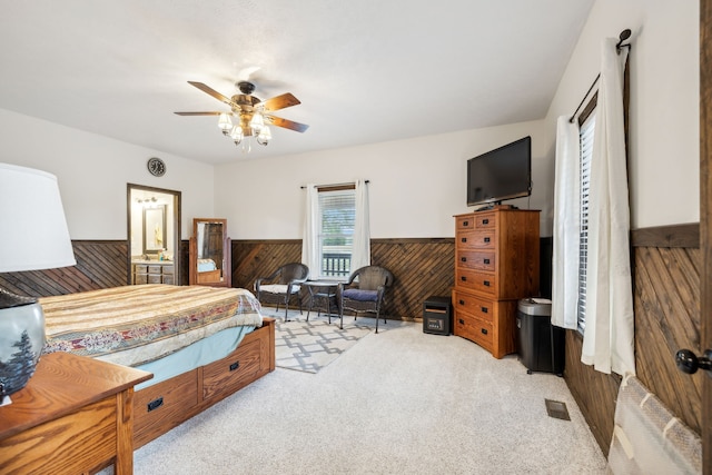 carpeted bedroom featuring ceiling fan and wooden walls