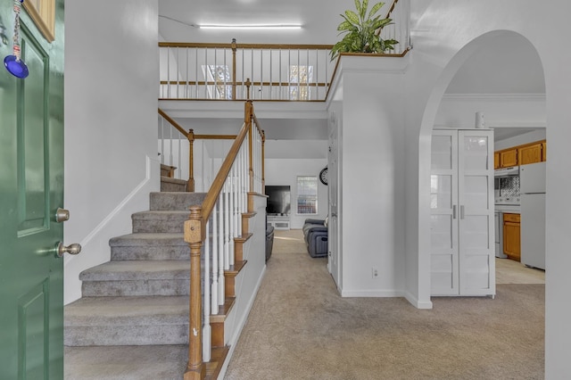 staircase with carpet floors and ornamental molding