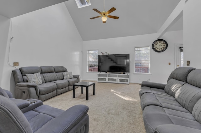 carpeted living room with a skylight, ceiling fan, and high vaulted ceiling