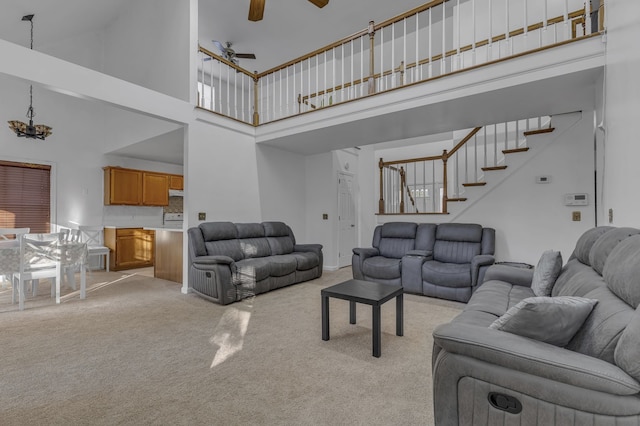 carpeted living room featuring ceiling fan and a towering ceiling