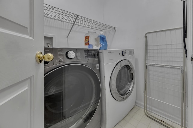 clothes washing area featuring light tile patterned flooring and washing machine and dryer