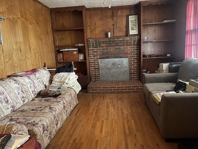 living room featuring hardwood / wood-style floors, a brick fireplace, built in features, and wooden walls