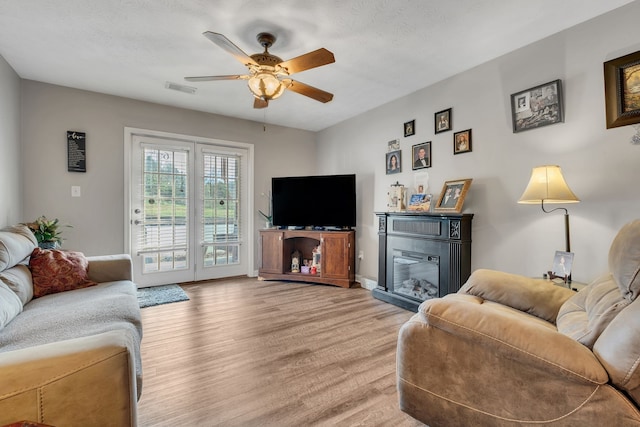 living room featuring ceiling fan, wood-type flooring, and a textured ceiling