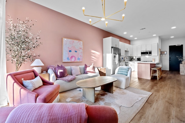 living room with an inviting chandelier, light hardwood / wood-style flooring, and sink