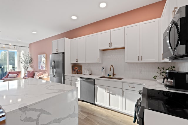 kitchen featuring white cabinets, sink, light hardwood / wood-style floors, light stone counters, and stainless steel appliances