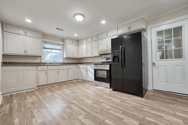 kitchen featuring black refrigerator with ice dispenser, crown molding, light hardwood / wood-style flooring, white cabinets, and stainless steel stove